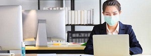 Woman wearing a mask working at a computer in an office