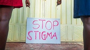 Two people pointing to a sign that says stop stigma