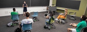 A professor teaching a class with students wearing a mask and being physically distanced